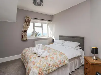 a bedroom with a bed with a teddy bear on it at Mynydd ar Mor in Barmouth