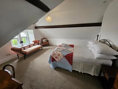 a bedroom with a bed and a couch in a room at Y Garth, Sleeps 12 in Barmouth