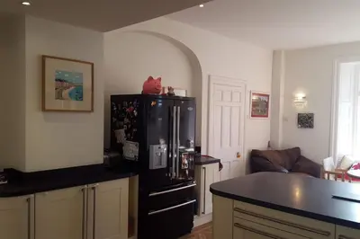 a kitchen with a black refrigerator and a table at Y Garth, Sleeps 12 in Barmouth