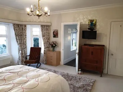 a bedroom with a bed and a television and a chandelier at Y Garth, Sleeps 12 in Barmouth