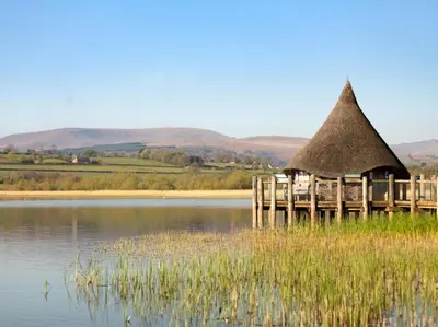 a hut with a thatched roof on a lake at 3 Bed in Brecon oc-93947 in Llanywern