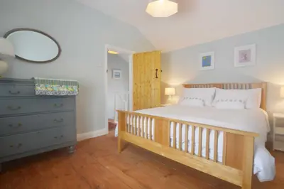 a bedroom with a bed and a dresser and a mirror at Y Bwthyn Aberaeron in Aberaeron