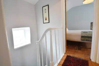 a hallway with a stairway with a bed and a window at Y Bwthyn Aberaeron in Aberaeron