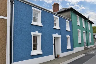 a row of blue and green houses on a street at Y Bwthyn Aberaeron in Aberaeron