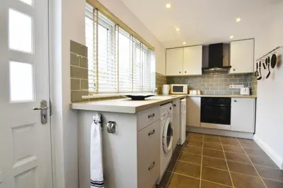 a kitchen with white cabinets and a washer and dryer at Y Bwthyn Aberaeron in Aberaeron