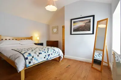 a bedroom with a bed and a mirror on the wall at Y Bwthyn Aberaeron in Aberaeron
