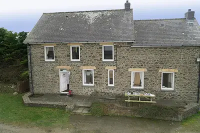 a brick house with a bench in front of it at Brynonnen Llangrannog in Llanllwchaiarn
