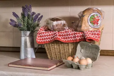 a basket of eggs on a counter with a vase of flowers at Brynonnen Llangrannog in Llanllwchaiarn