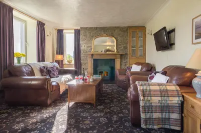 a living room with leather furniture and a fireplace at Brynonnen Llangrannog in Llanllwchaiarn