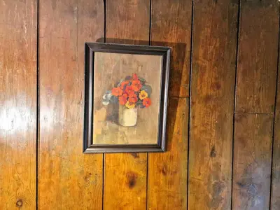 a painting of a vase of flowers on a wooden wall at Arwel Llangrannog in Llanllwchaiarn