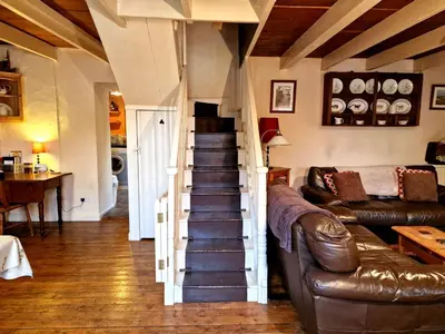 a living room with a staircase and a couch at Arwel Llangrannog in Llanllwchaiarn