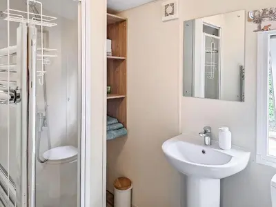 a white bathroom with a sink and a shower at Glen Y Nant in Llanfihangel-nant-Melan