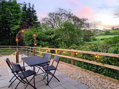 a table and chairs on a patio with a fence at Glen Y Nant in Llanfihangel-nant-Melan