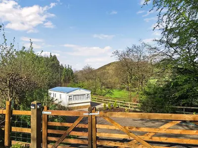 a wooden fence with a gate in front of a building at Glen Y Nant in Llanfihangel-nant-Melan