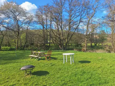 a picnic table and a table in a field at Glen Y Nant in Llanfihangel-nant-Melan
