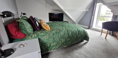 a bedroom with a bed with a green blanket at The Penthouse NY Loft Apartment in Barmouth