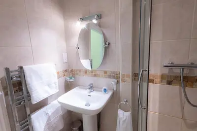 a bathroom with a sink and a shower with a mirror at Plas Hafan Apartment 2 Aberystwyth in Aberystwyth