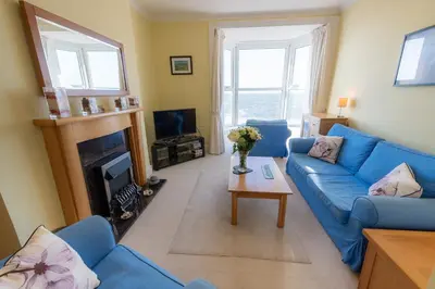 a living room with a blue couch and a fireplace at Plas Hafan Apartment 2 Aberystwyth in Aberystwyth