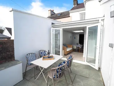 a patio with a white table and chairs at Brodawel New Quay in New Quay
