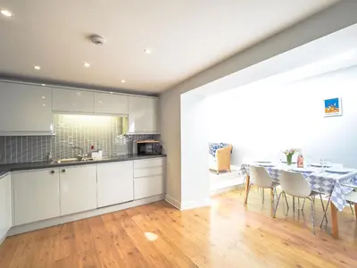a kitchen and dining room with a table and chairs at Brodawel New Quay in New Quay
