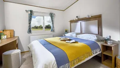 a bedroom with a large bed with a yellow and blue blanket at WH - Smugglers Cove 01 in Aberaeron