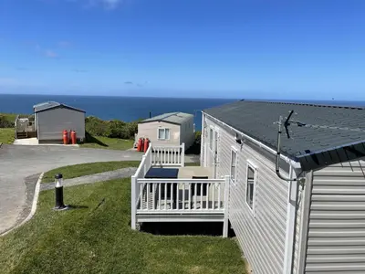 a small white house with a porch and the ocean at WH - Smugglers Cove 03 in Aberaeron