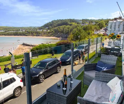 a balcony with a view of a beach and cars parked at No. 1 Cliffside New Quay in New Quay