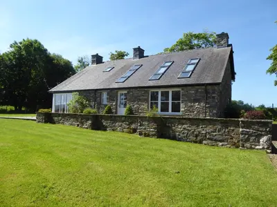 a stone house with solar panels on the roof at Bryn Isaf Tregaron in Ystrad-Meurig