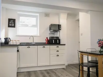 a kitchen with white cabinets and a sink and a window at Henllys in Harlech