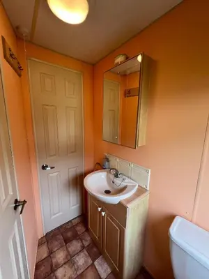 a bathroom with a sink and a mirror and a toilet at Spacious 2 bedroomed mobile home in Aberystwyth
