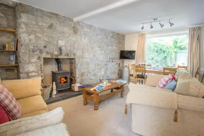 a living room with a stone wall with a fireplace at Ellesmere New Quay in New Quay