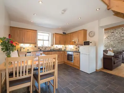 a kitchen with a table and a white refrigerator at Briallen Aberystwyth in Llanrhystyd