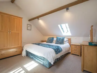 a bedroom with a large bed with blue pillows at Briallen Aberystwyth in Llanrhystyd