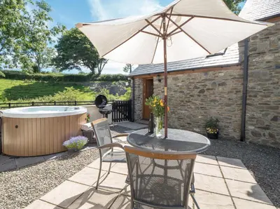 a table with an umbrella next to a hot tub at Briallen Aberystwyth in Llanrhystyd