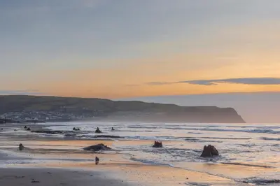 a beach with a group of people in the ocean at Cae Mawr Borth and Ynyslas in Scyborycoed