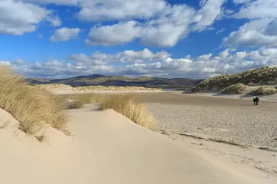 a person walking on the sand in the desert at Cae Mawr Borth and Ynyslas in Scyborycoed