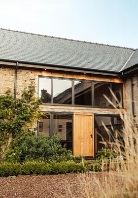 a brick house with glass windows and a wooden door at The Granary Wales in Kington