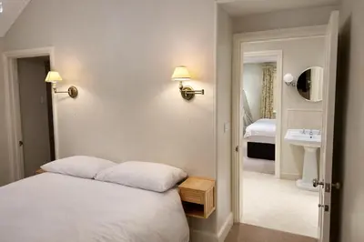 a bedroom with a bed and a bathroom with a sink at Glandwr hall - 6 Bed - Magnificent Country House with Heated Swimming Pool & Jacuzzi in Barmouth