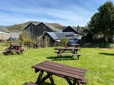 a group of picnic tables in a field at Aleppo Merchant Inn in Carno