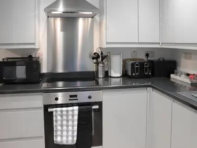 a kitchen with white cabinets and a stove top oven at Llety Cariad in Bala
