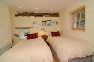 two twin beds in a room with a window at The Old Mill Devils Bridge in Llanilar