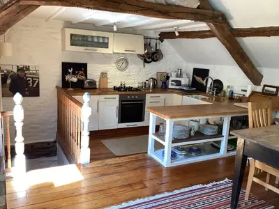 a kitchen with white cabinets and a wooden floor at The Old Mill Devils Bridge in Llanilar