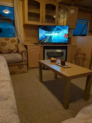 a living room with a coffee table and a tv at 64 Wide Horizon in Aberaeron