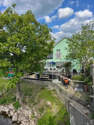 a house with a tree next to a river at By the River in Glasbury