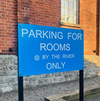 a blue parking sign in front of a brick building at By the River in Glasbury