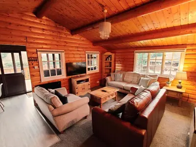 a living room with leather furniture in a log cabin at Serene Snowdonia Retreat in Trawsfynydd