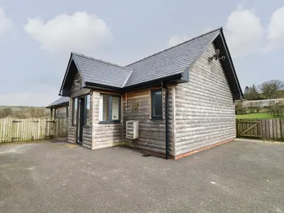 a small wooden house with a parking lot at Caban Dulas in Rhayader