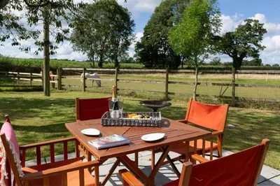 a wooden table with chairs and a bottle of wine at Stunning studio flat with dedicated private garden in Shrewsbury