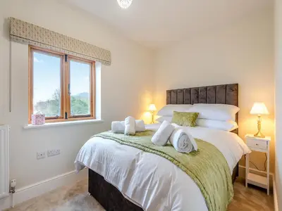 a bedroom with a bed with white sheets and a window at Nupton Hop Kiln in Kings Pyon