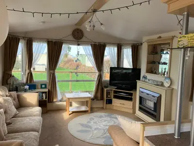 a living room with a couch and a television at Cosy caravan Sunbeach in Llwyngwril